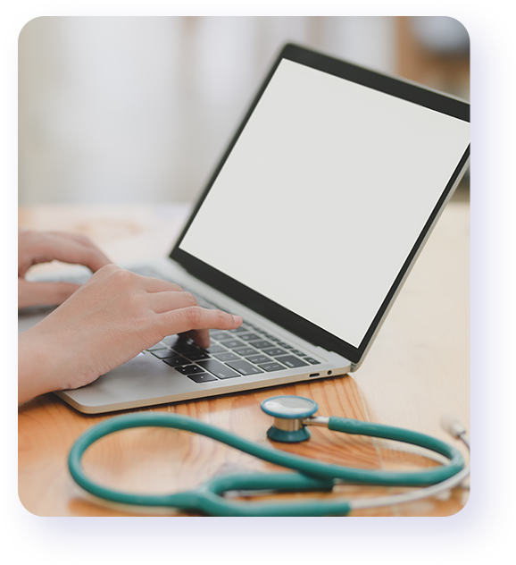 A person using a laptop with stethoscope on the table.